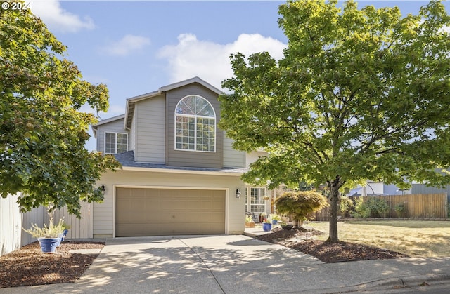 traditional-style house featuring a garage, concrete driveway, and fence