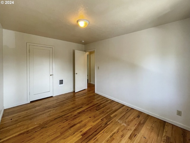 unfurnished bedroom featuring a closet and hardwood / wood-style flooring