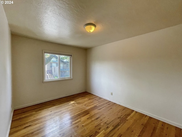 empty room with light hardwood / wood-style floors and a textured ceiling