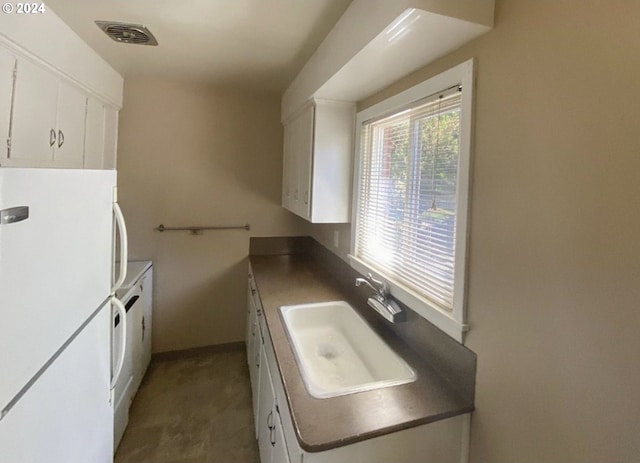 kitchen with white cabinetry, sink, and white fridge