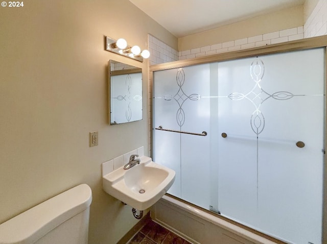 full bathroom featuring sink, toilet, and bath / shower combo with glass door