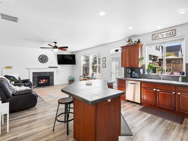 kitchen with dishwasher, light hardwood / wood-style floors, tile counters, and a wealth of natural light