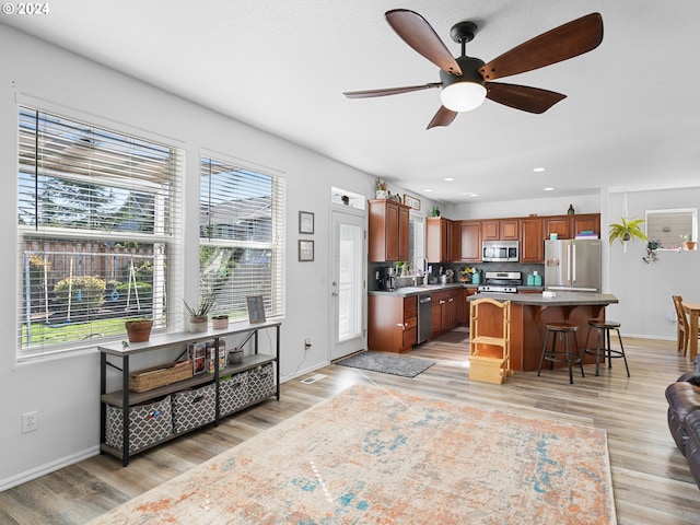 kitchen with a kitchen breakfast bar, a kitchen island, stainless steel appliances, and a wealth of natural light