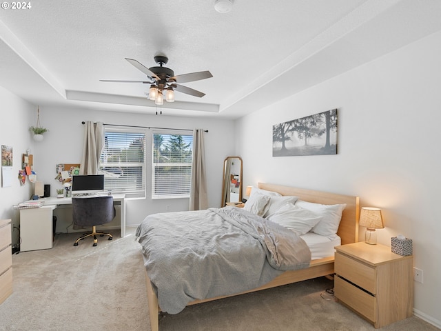 carpeted bedroom with ceiling fan, a textured ceiling, and a raised ceiling