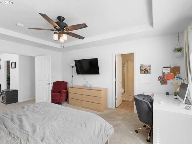 bedroom with a raised ceiling, ceiling fan, and light carpet