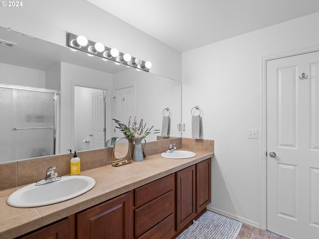 bathroom featuring tile patterned flooring, vanity, and a shower with shower door