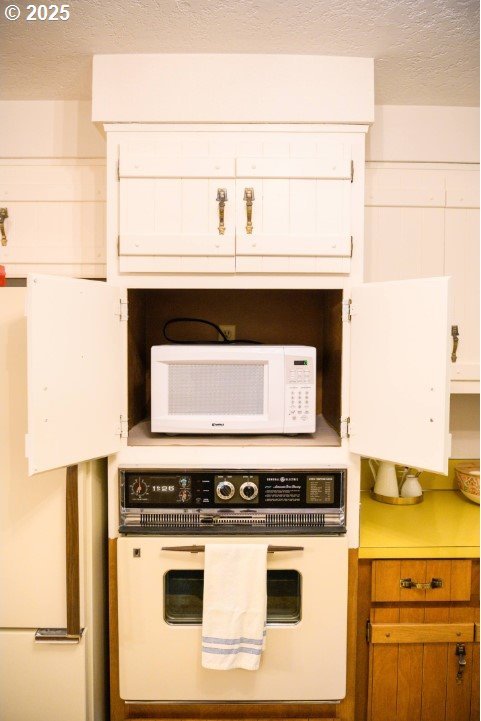 68191 E Twinberry Loop, Welches, OR 97067 - kitchen with white appliances, light countertops, a textured ceiling, brown cabinetry, and white cabinetry