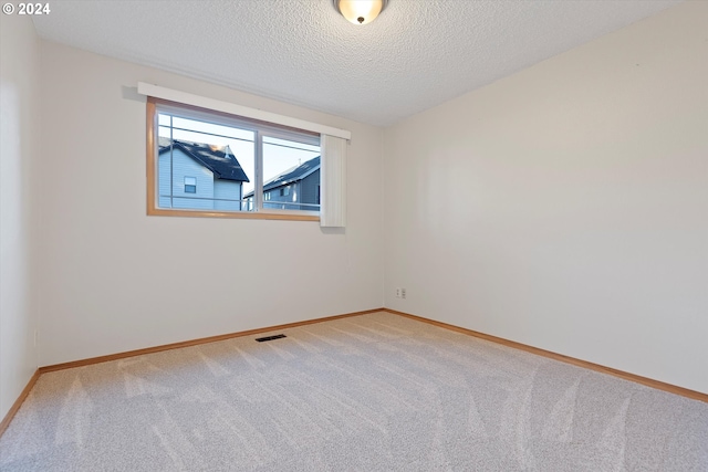 carpeted spare room with a textured ceiling