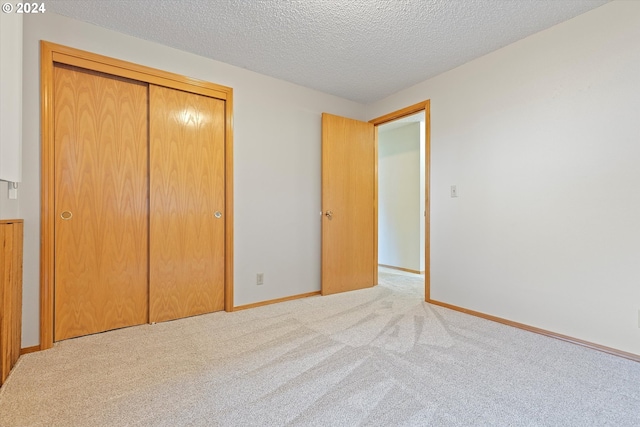 unfurnished bedroom featuring a textured ceiling, light colored carpet, and a closet