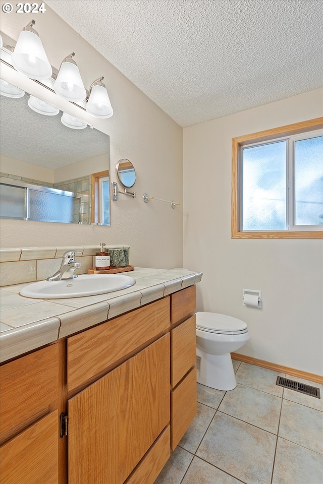 bathroom with walk in shower, a textured ceiling, vanity, and toilet