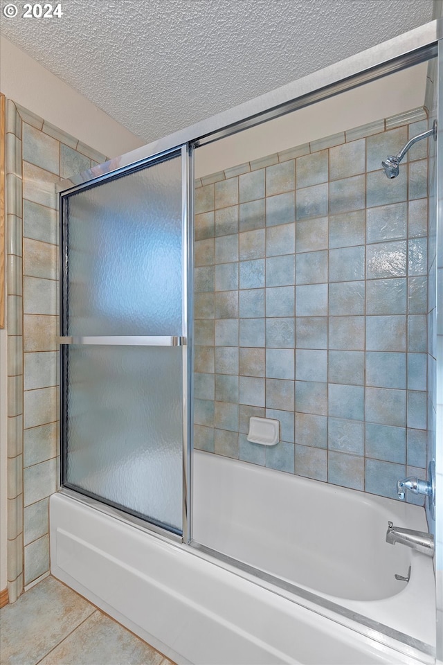 bathroom with tile patterned flooring, a textured ceiling, and enclosed tub / shower combo