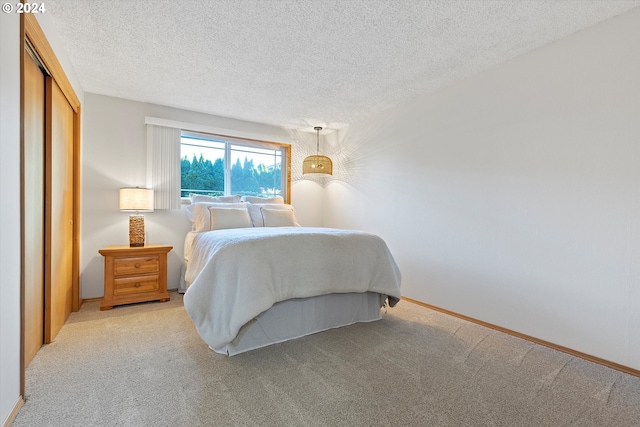 bedroom featuring light colored carpet, a textured ceiling, and a closet