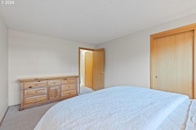 carpeted bedroom featuring a closet and a textured ceiling