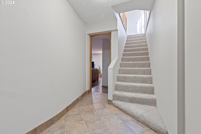 stairs with a textured ceiling and tile patterned floors