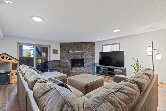 living room with a textured ceiling, wood-type flooring, and a fireplace