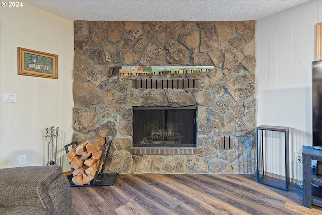 room details with a textured ceiling, hardwood / wood-style floors, and a stone fireplace