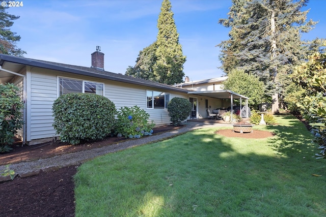 rear view of property with a fire pit and a yard