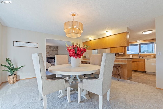 dining room with a textured ceiling, a fireplace, sink, and light carpet