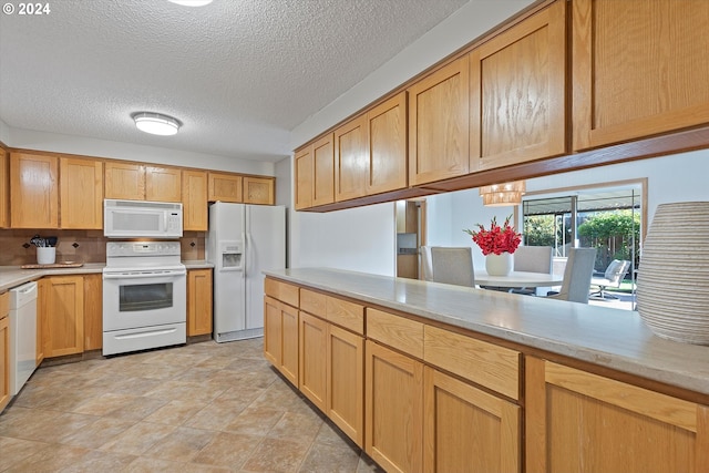 kitchen with a textured ceiling, white appliances, and light tile patterned floors