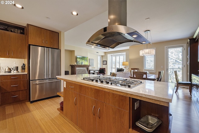 kitchen featuring light hardwood / wood-style flooring, island exhaust hood, decorative light fixtures, a kitchen island, and appliances with stainless steel finishes