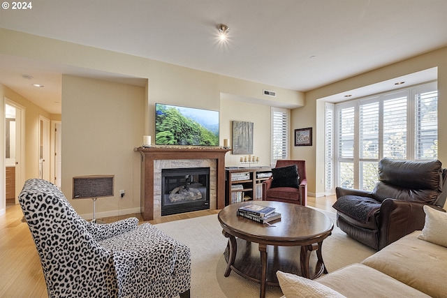 living room with light wood-type flooring and a tiled fireplace