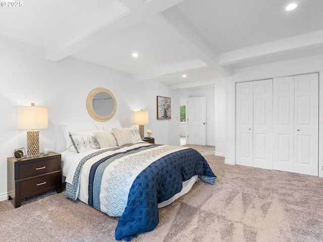 bedroom featuring beam ceiling, light colored carpet, and a closet