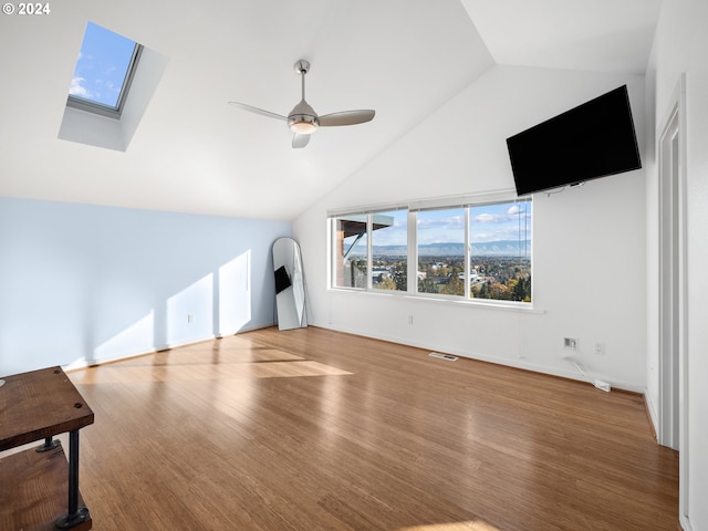 unfurnished living room with lofted ceiling with skylight, hardwood / wood-style flooring, and ceiling fan