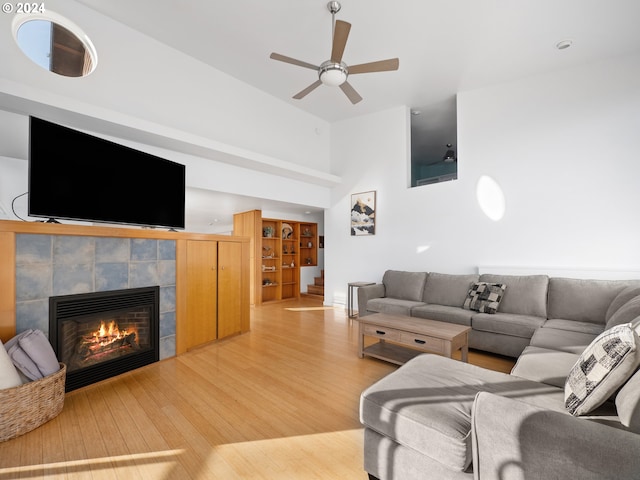 living room with a tiled fireplace, hardwood / wood-style flooring, and ceiling fan