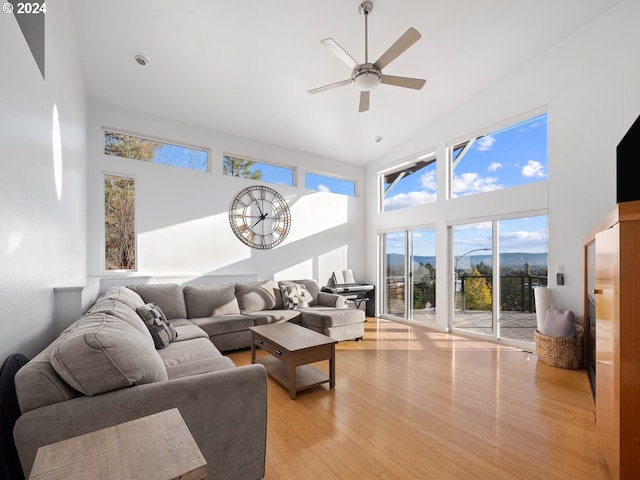 living room featuring ceiling fan, high vaulted ceiling, and light wood-type flooring