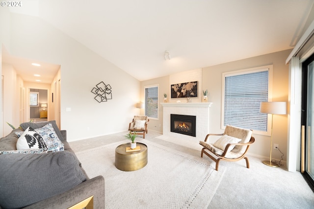 carpeted living room featuring lofted ceiling and a brick fireplace