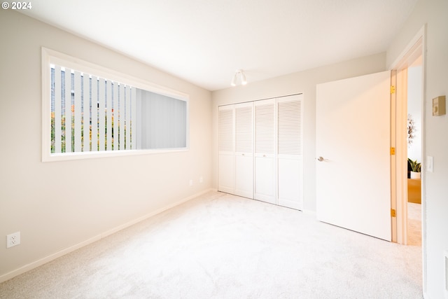 unfurnished bedroom with light carpet and a closet