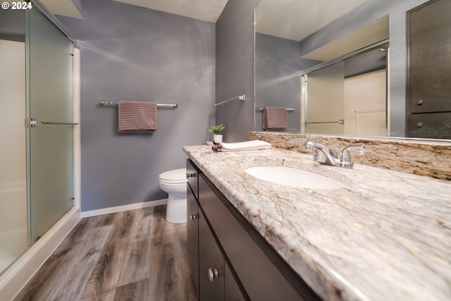 bathroom featuring vanity, toilet, wood-type flooring, and a shower with door