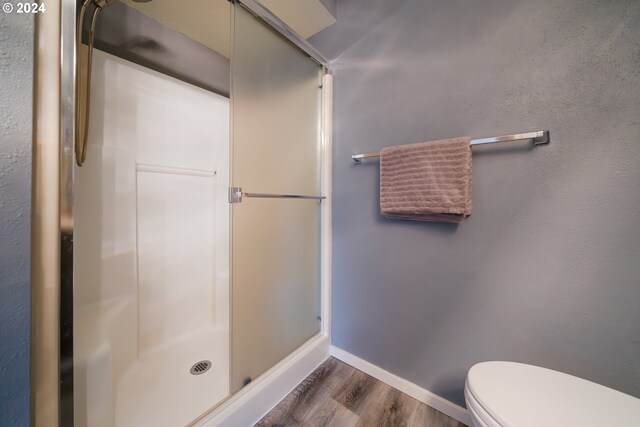 bathroom featuring wood-type flooring, toilet, and walk in shower