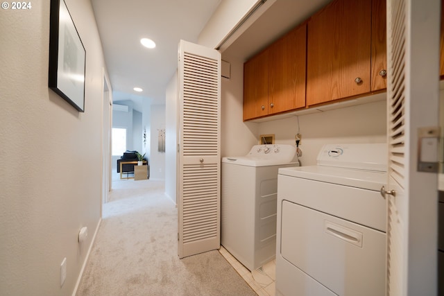 laundry room with independent washer and dryer, cabinets, and light colored carpet