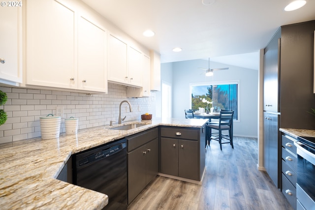 kitchen with sink, dishwasher, vaulted ceiling, white cabinets, and light hardwood / wood-style flooring