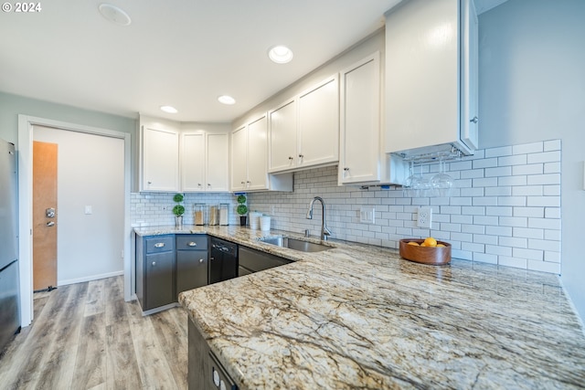 kitchen with light hardwood / wood-style floors, white cabinetry, light stone countertops, and sink