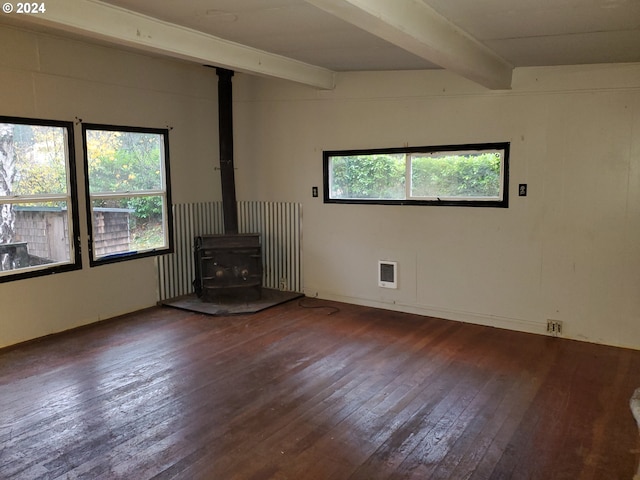 unfurnished living room with hardwood / wood-style flooring, a healthy amount of sunlight, a wood stove, and beamed ceiling