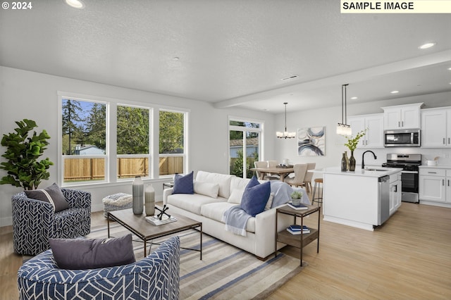 living room featuring a textured ceiling, light hardwood / wood-style floors, a chandelier, and sink