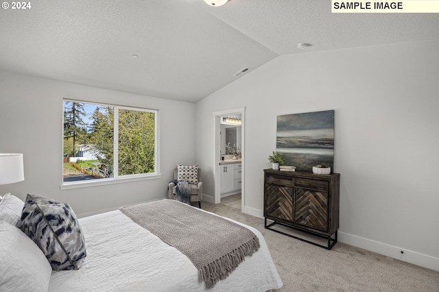 carpeted bedroom with a textured ceiling, lofted ceiling, and connected bathroom