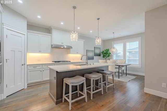 kitchen featuring sink, hardwood / wood-style flooring, a kitchen island with sink, and white cabinetry