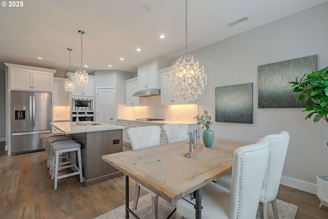 dining space with sink, dark hardwood / wood-style floors, and an inviting chandelier