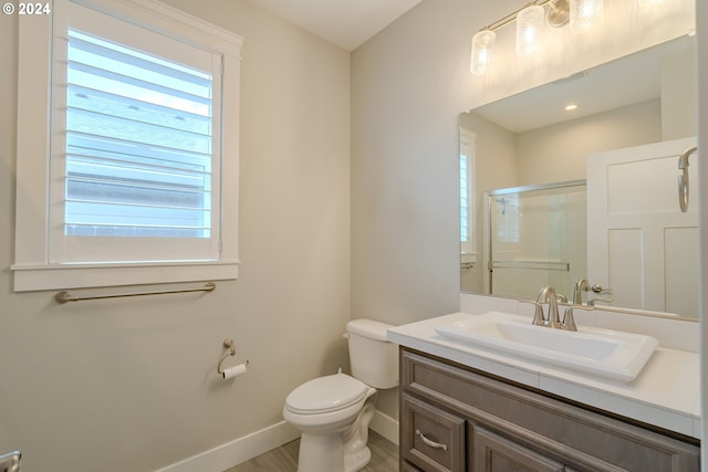 bathroom with a shower with shower door, toilet, and vanity