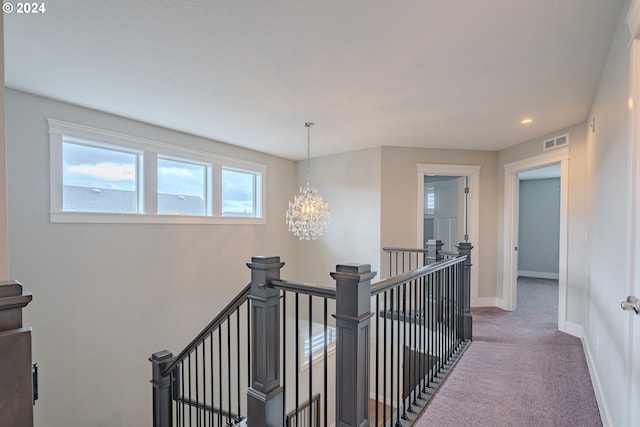 hallway featuring carpet flooring and an inviting chandelier