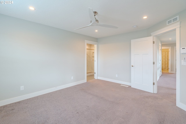 unfurnished bedroom featuring light carpet, connected bathroom, and ceiling fan