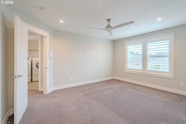 empty room with ceiling fan, light carpet, and washer and dryer