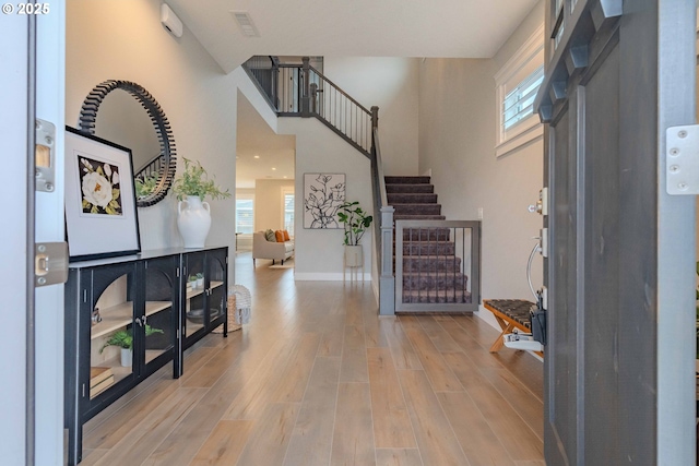 foyer with light hardwood / wood-style floors and a towering ceiling