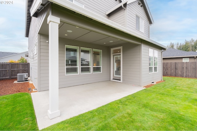 rear view of property with a patio area, central AC unit, and a yard