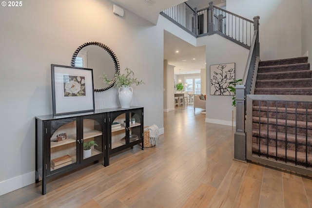 foyer with hardwood / wood-style floors and a towering ceiling