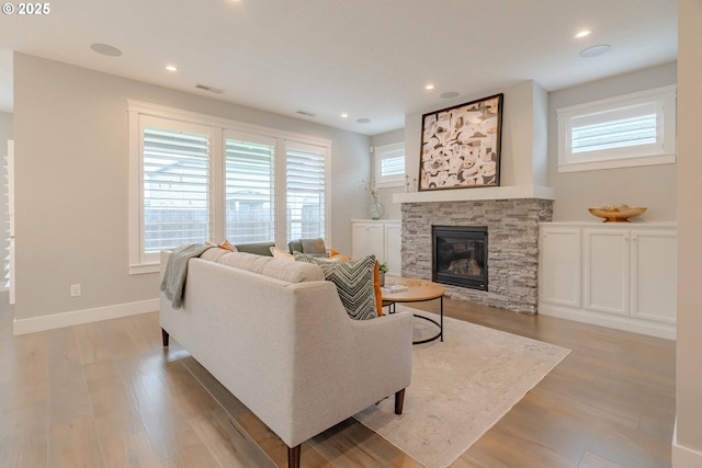 living room featuring a stone fireplace and light hardwood / wood-style floors