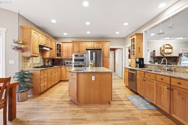 kitchen featuring a center island with sink, decorative backsplash, light stone countertops, appliances with stainless steel finishes, and light hardwood / wood-style floors